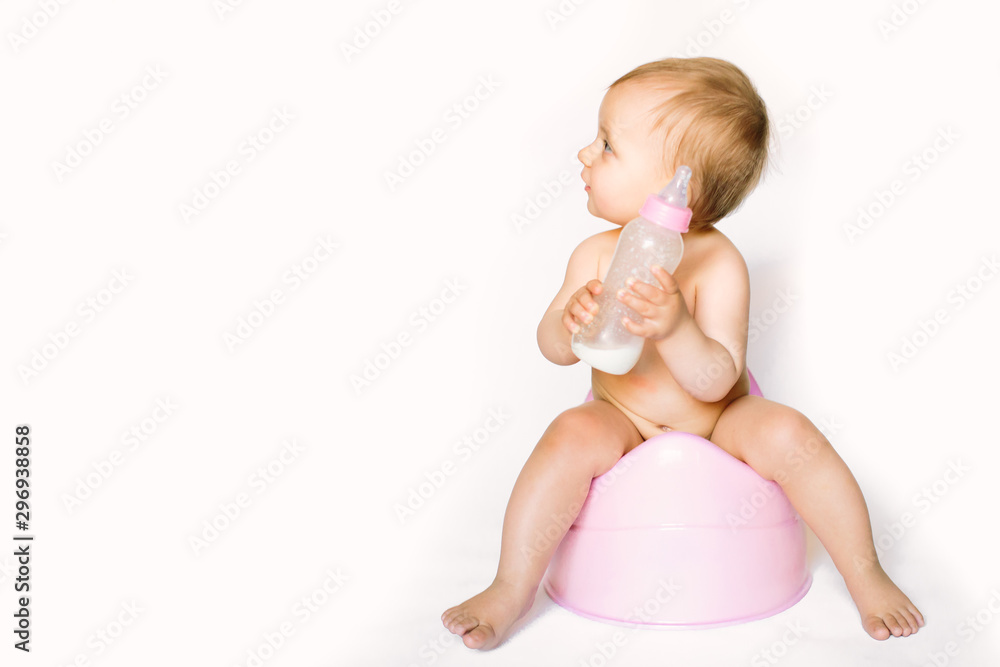 Charming photo of cute baby girl holding a boottle with baby milk and sitting on a pink potty. Isolated on white background Charming photo of cute baby girl holding a boottle with baby milk and sitting on a pink potty. Isolated on white background