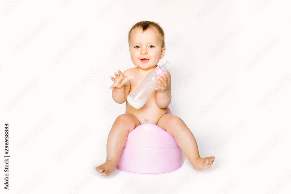 Charming photo of cute baby girl holding a boottle with baby milk and sitting on a pink potty. Isolated on white background Charming photo of cute baby girl holding a boottle with baby milk and sitting on a pink potty. Isolated on white background