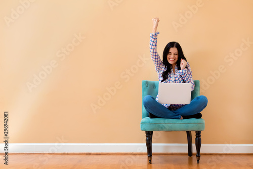 Εκτύπωση καμβά Young woman with a laptop computer with successful pose sitting in a chair