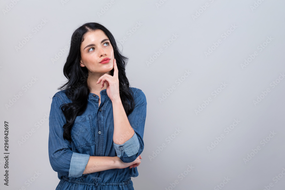 Young woman in a thoughtful pose on a gray background Young woman in a thoughtful pose on a gray background