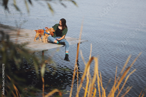 Girl with her dog, English Cocker Spaniel, sitting on the bench near the lake