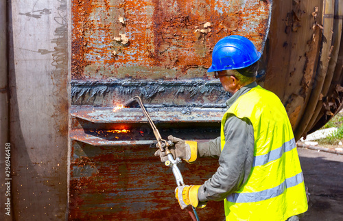 Tablou pe pânză Worker is cutting old metal industrial equipment with acetylene torch