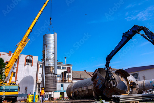 Gripper machine with mobile crane are lay down big old metal tanks