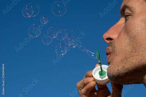 man with colorful and reflective soap bubbles floating in the blue sky
