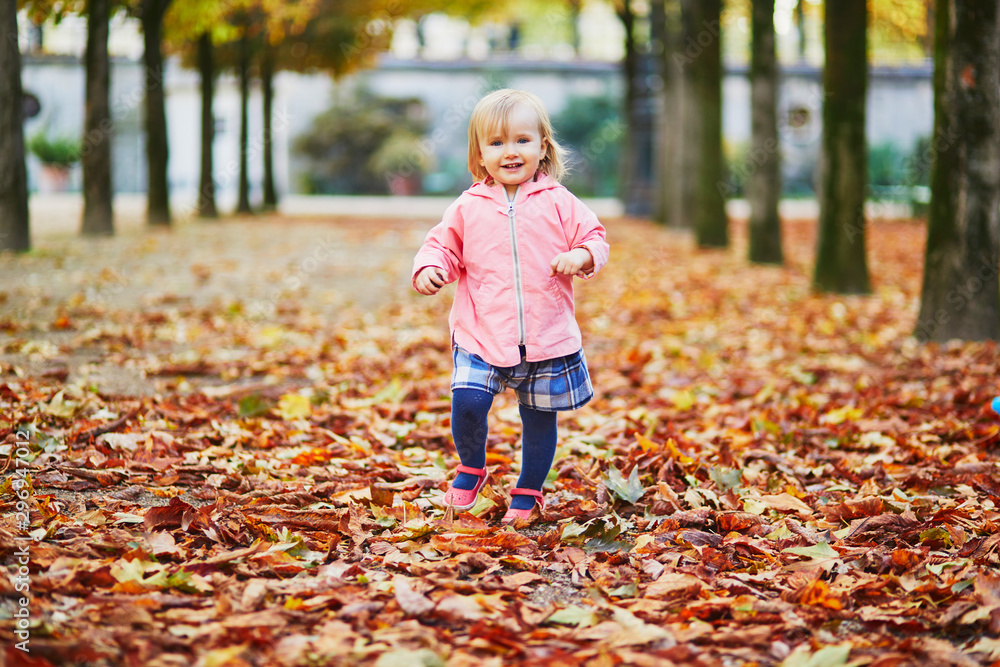Adorable cheerful toddler girl running in Tuileries garden in Paris, France Adorable cheerful toddler girl running in Tuileries garden in Paris, France