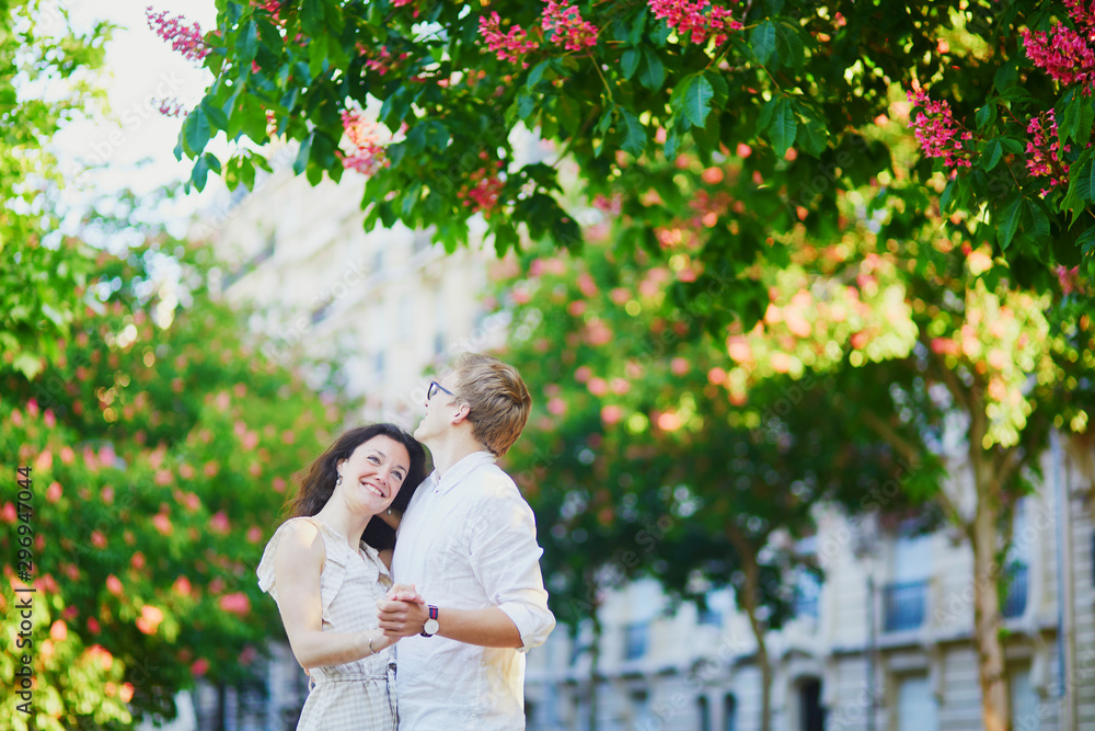 Happy romantic couple in Paris, hugging under pink chestnuts in full bloom