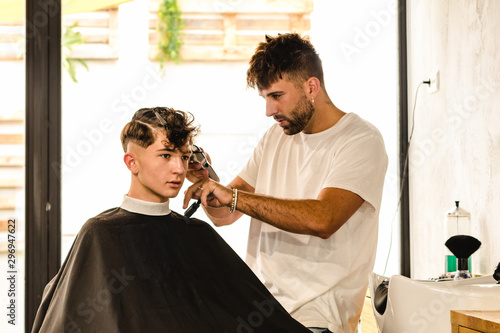 Confident teenager visiting hairstylist in barber shop