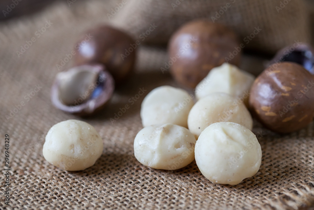Macadamia nuts on sackcloth and wooden background