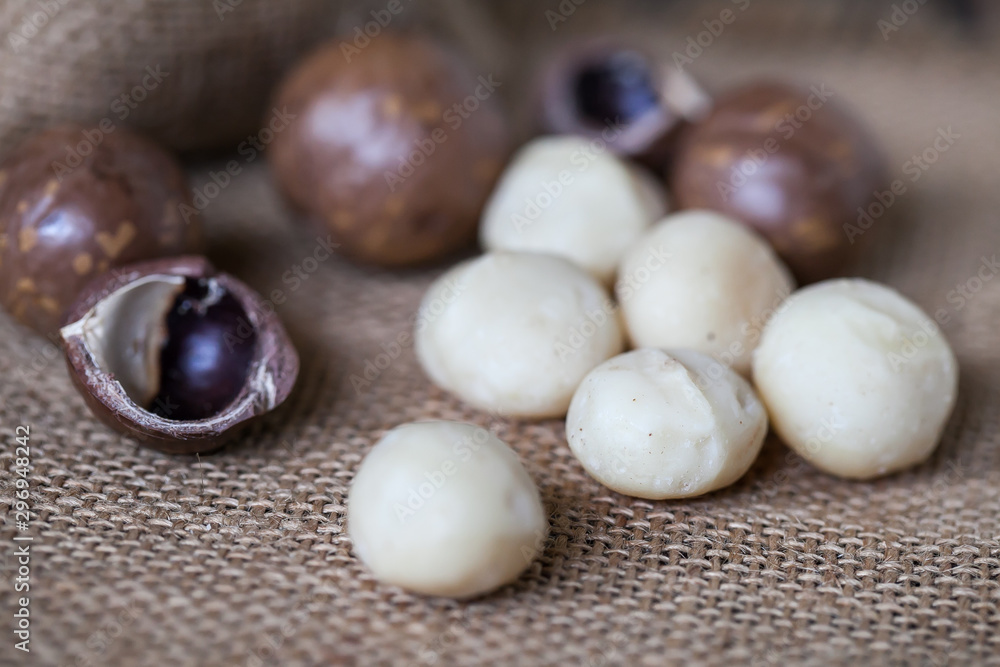 Macadamia nuts on sackcloth and wooden background Macadamia nuts on sackcloth and wooden background