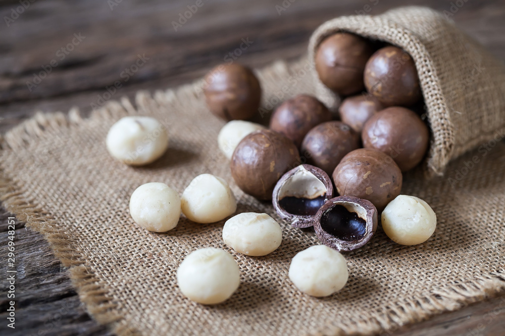 Macadamia nuts on sackcloth and wooden background Macadamia nuts on sackcloth and wooden background
