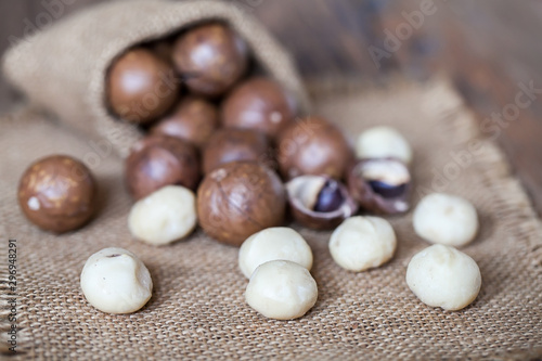 Macadamia nuts on sackcloth and wooden background