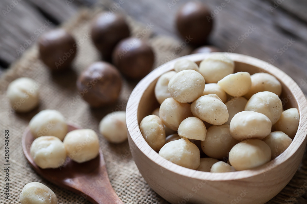 Macadamia nuts on sackcloth and wooden background Macadamia nuts on sackcloth and wooden background