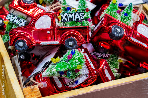 Close up a wooden box with a bunch of Christmas decorations in the form of a red car (truck) with a decorated Christmas tree in the back and the inscription " Merry Christmas"