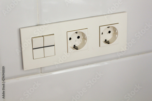 Two white socket and switch on the wall with tiles in the hotel bathroom with white tiles on the wall. Bathroom luxury interior 
