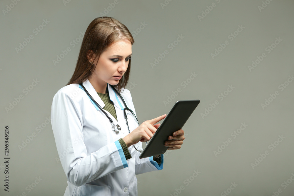beautiful brunette female doctor on a gray background with a tablet in hands beautiful brunette female doctor on a gray background with a tablet in hands