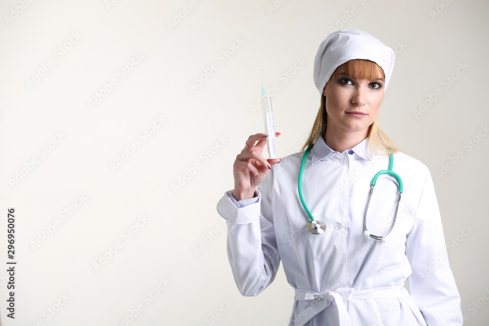 female doctor in white coat with stethoscope and syringe on gray background female doctor in white coat with stethoscope and syringe on gray background