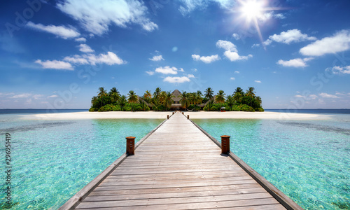 Tropisches Reisekonzept: Holzsteg führt auf eine tropische Insel mit türkisem Ozean, Kokosnusspalmen und feinem Sandstrand, Malediven