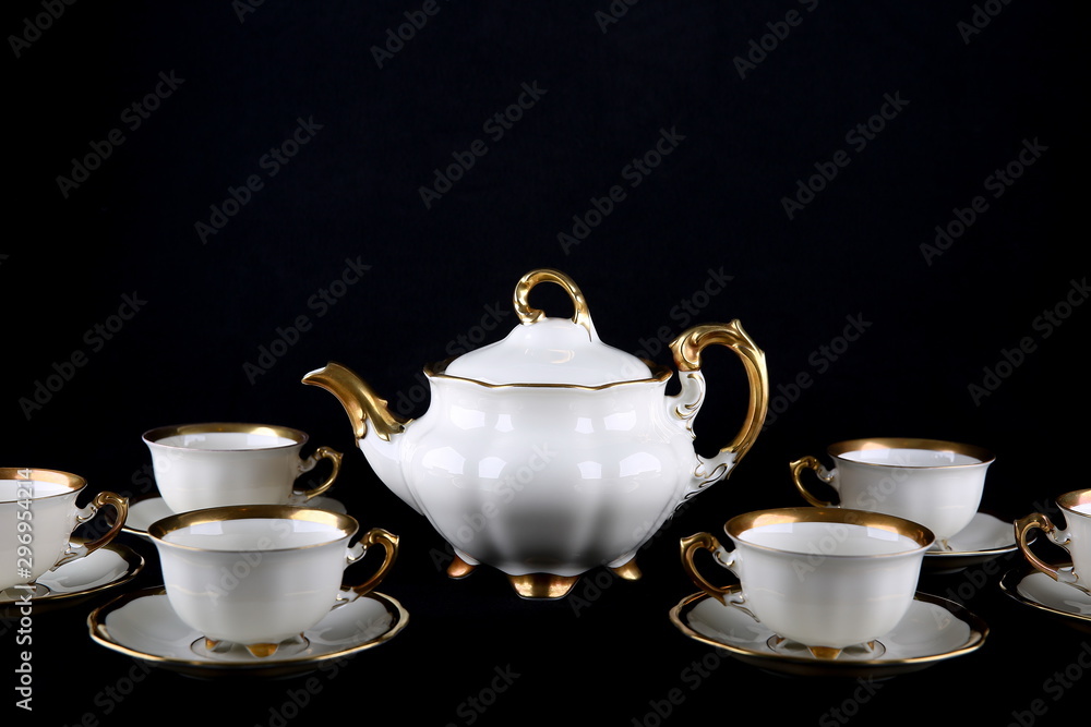 Vintage white tea set with gilding on a black background. porcelain teapot and cups on a dark background