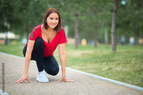beautiful adult woman goes in for sports in the summer park