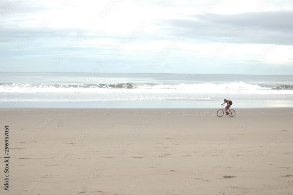 Man walking on the coast of the beach with clear water and blue sky in the background with the sun's rays at sunset. Man walking on the coast of the beach with clear water and blue sky in the background with the sun's rays at sunset.