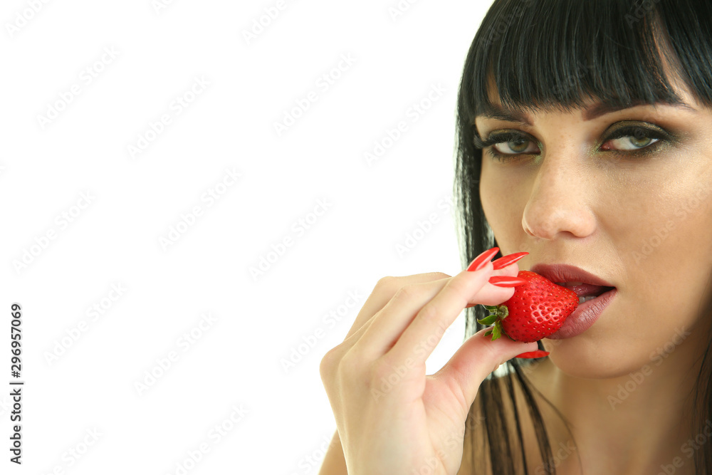 sexy woman bites strawberries on a white background. beautiful young brunette with red manicure holds a strawberry in her hand near her lips. sexy woman bites strawberries on a white background. beautiful young brunette with red manicure holds a strawberry in her hand near her lips.