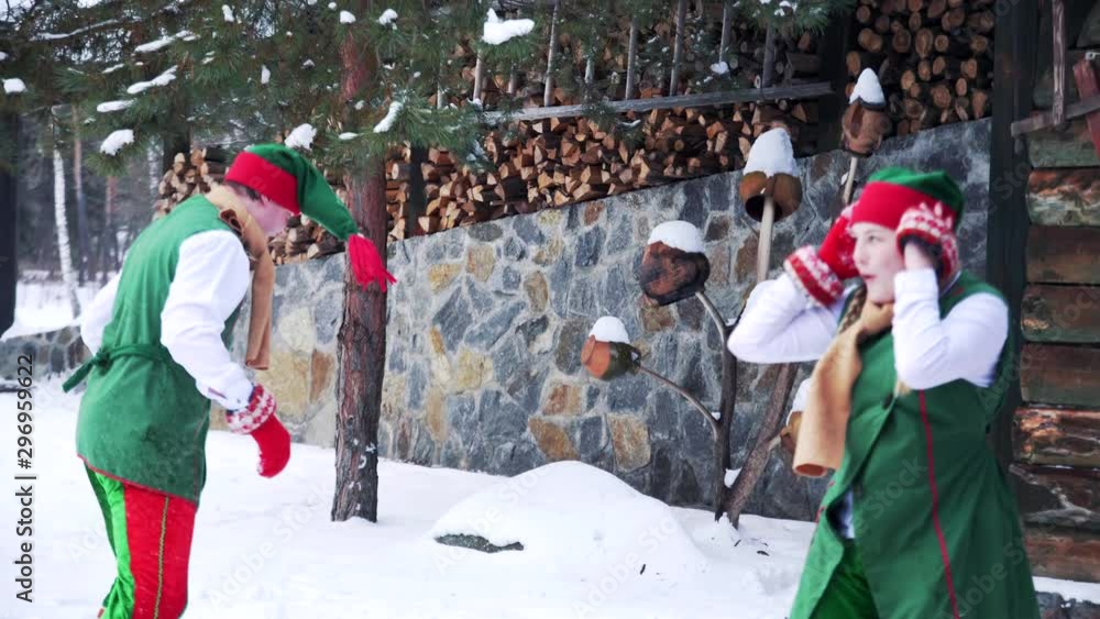 Joyful elves playing in the snow near the house. Fairy heroes elves a boy and a girl having snowball fight on winter holidays.
