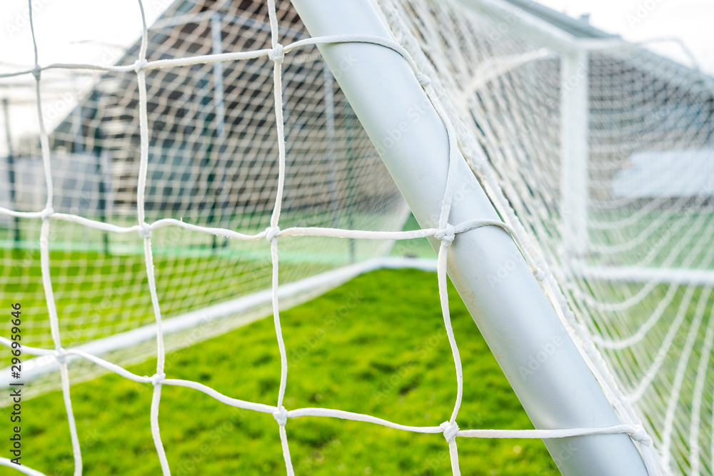 Shallow focus of a newly delivered football goal located in a village park. Detail of the white netting and knots are visible. - obrazy, fototapety, plakaty 