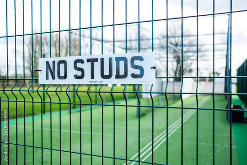 Shallow focus of a newly installed village cricket netting showing detail of the No Studs sign on the wire entrance. Used for cricket club practicing