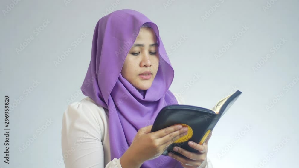 Beautiful Asian muslim woman wearing hijab reading the holy book, reciting Quran islamic holy book Beautiful Asian muslim woman wearing hijab reading the holy book, reciting Quran islamic holy book