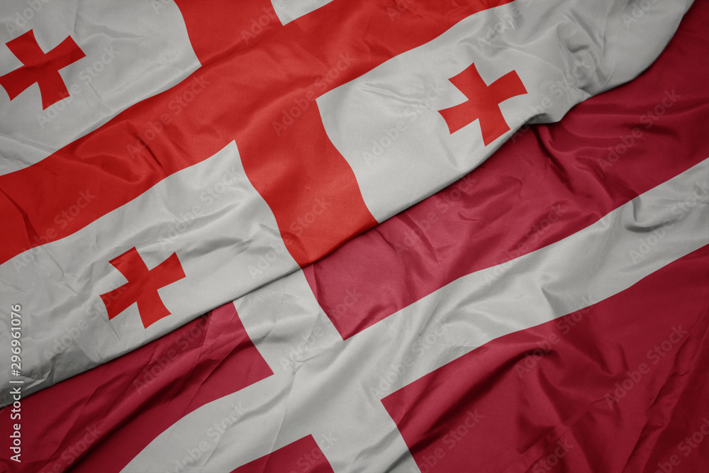 Fototapeta premium waving colorful flag of denmark and national flag of georgia.