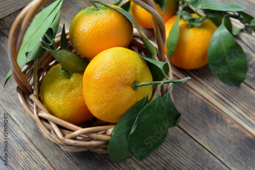 Ripe tangerines with leaves in a basket