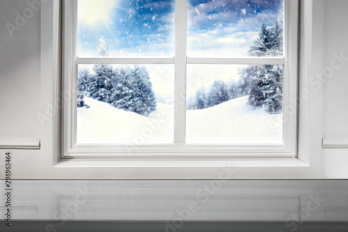 Blurred snowy winter sunshine landscape outside the window kitchen  with table top for products and decorations.