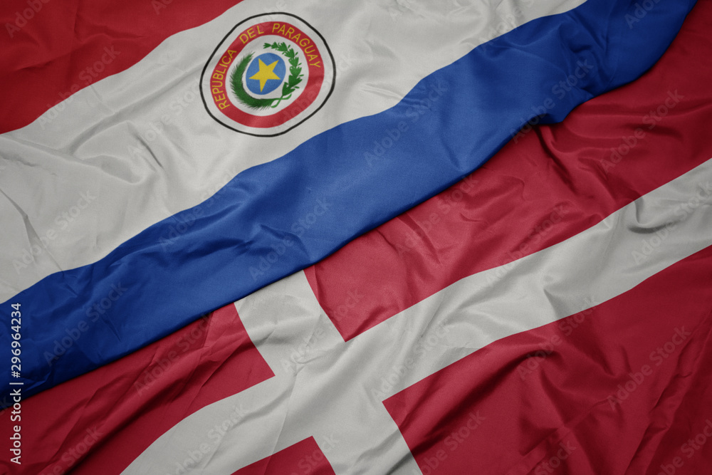 Fototapeta premium waving colorful flag of denmark and national flag of paraguay.