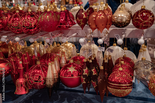 Golden and red glass baubles Christmas ornaments are hanging on shelves at Christmas market in Europe. Holiday decorations. Christmas tree ornaments. New Year celebration background
