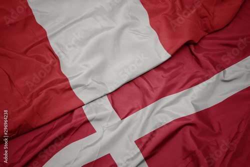 waving colorful flag of denmark and national flag of peru.