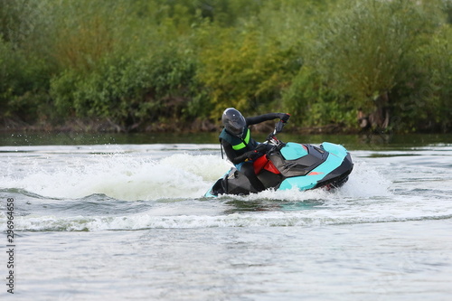 a man in a helmet and wetsuit performs tricks on a watercraft. beautiful photo of watercraft on the pond in motion with splashes of water.
