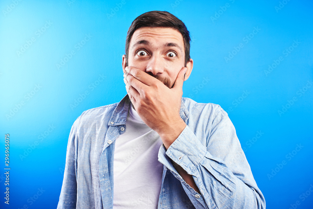 Tableau sur toile Surprised bearded man with shocked bulging eyes covers his mouth with hand isola