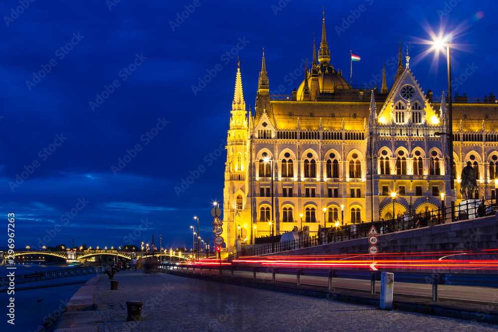 Hungarian Parliament building illuminated at night at the Danube riverside with the Margaret bridge at the background