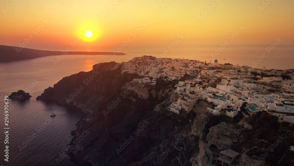 Aerial drone photo of world famous beautiful sunset at traditional and picturesque village of Oia with golden colours, Santorini island, Cyclades, Greece