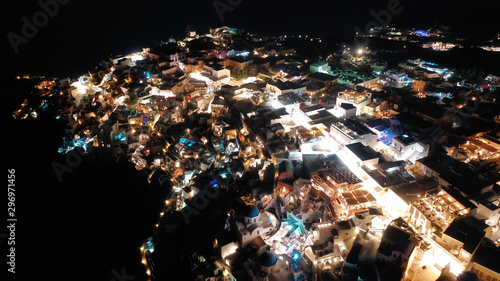 Aerial drone night shot of beautiful illuminated traditional and picturesque village of Oia built on a cliff  Santorini island  Cyclades  Greece