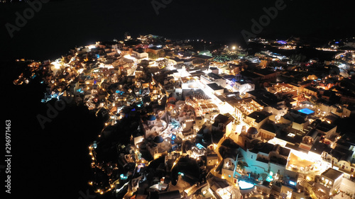 Aerial drone night shot of beautiful illuminated traditional and picturesque village of Oia built on a cliff, Santorini island, Cyclades, Greece