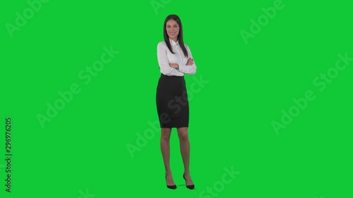 Happy confident beautiful caucasian business woman brunette smiling at camera with crossed hands. Full body isolated on green screen chroma key background