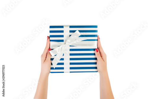 Woman hands give wrapped Christmas or other holiday handmade present in blue paper with white ribbon. Isolated on white background, top view. thanksgiving Gift box concept © sosiukin
