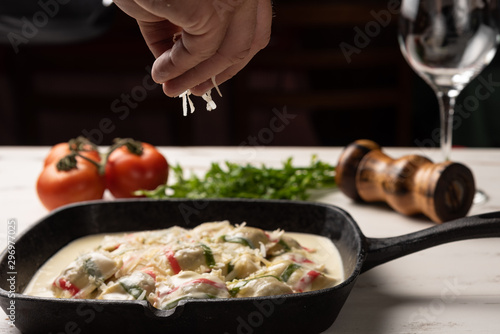 Handmade color ravioli pasta; Multi-colored ravioli pasta in a black iron pan, on wooden white table background.