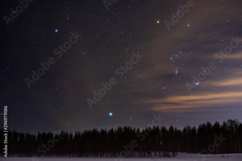 Orion and Canis Minor constellations and Sirius above boreal forest on a cold winter night
