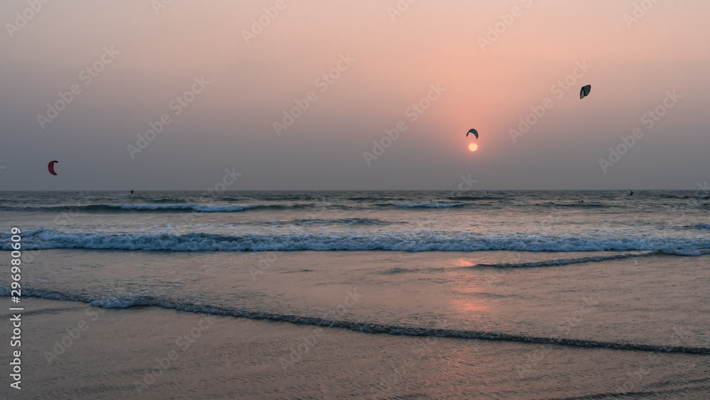Paragliding on sunset background. Tropical seascape: paragliderman jumps on horizon. Parachute canopy. Amazing scenery of ocean skyline on last sunny rays.