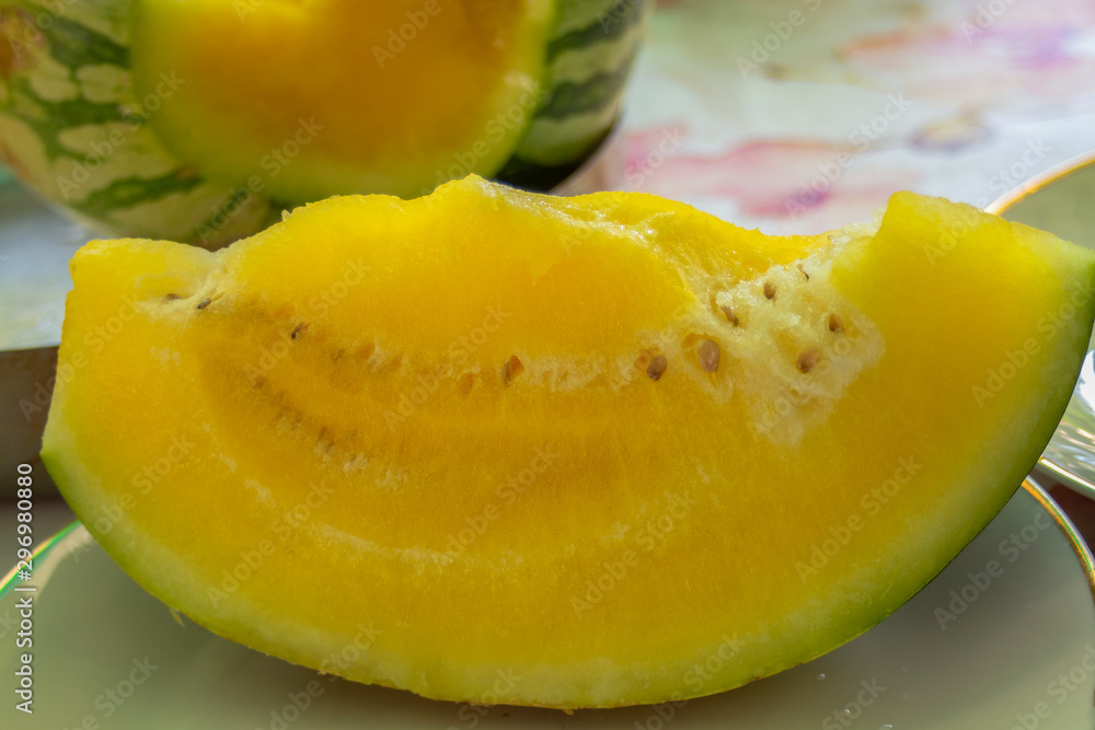 A slice of yellow watermelon against the background of the whole. A slice of yellow watermelon against the background of the whole.
