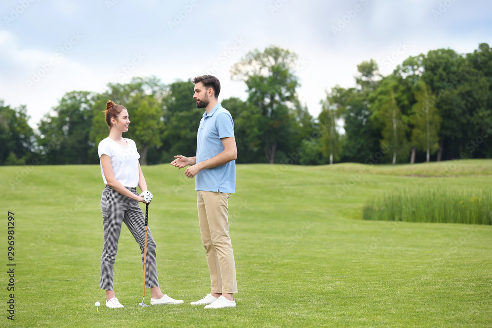 Coach teaching woman to play golf on green course