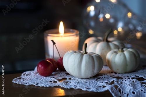 autumn and winter cozy table decoration with candle  small apples and white baby boo pumpkins