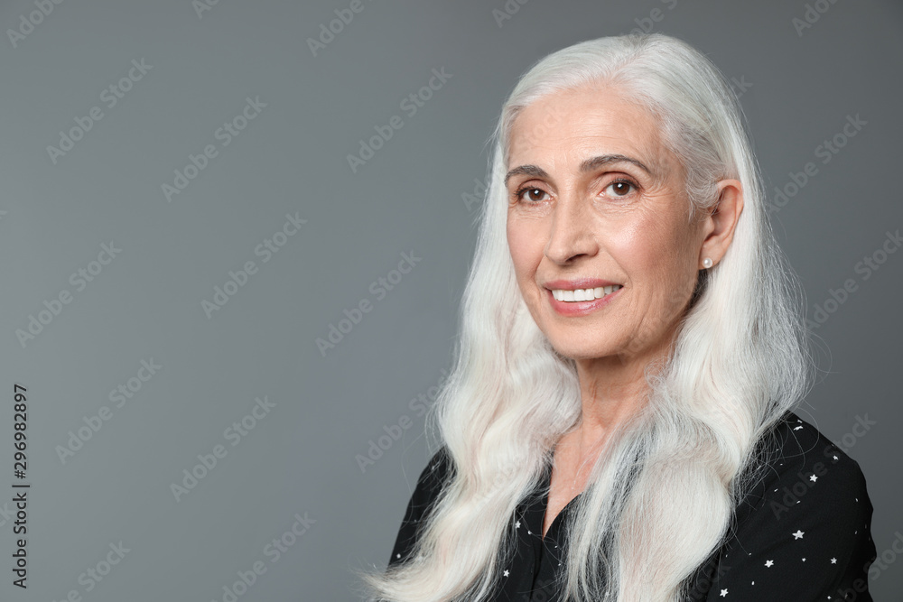 Portrait of beautiful mature woman on grey background, space for text Portrait of beautiful mature woman on grey background, space for text